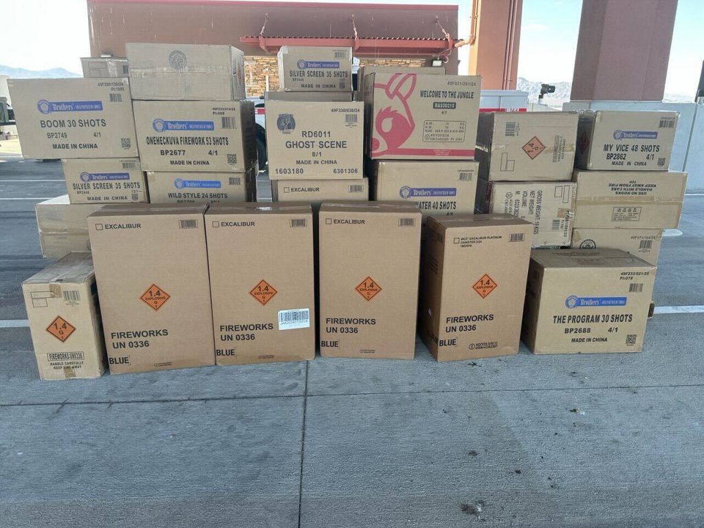 Dozens of stacked boxes labeled as fireworks are displayed at an inspection site.