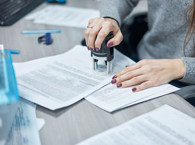 Girl puts a stamp on documents in the office