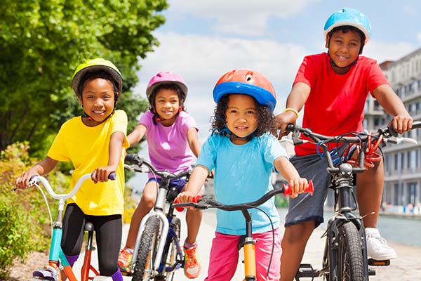 African children in safety helmets riding bikes in summer city