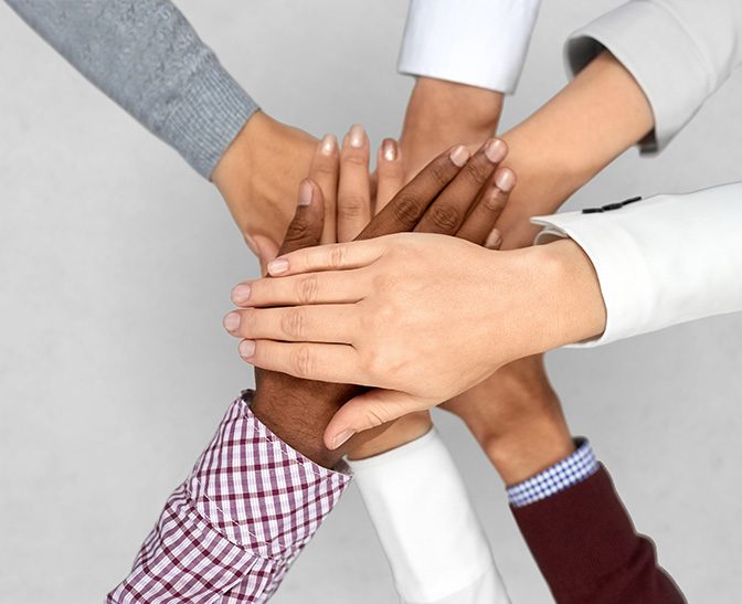 Hands from a diverse group of people stacked together in a gesture of unity and teamwork.