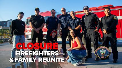 A group of San Bernardino County firefighters in uniform stand smiling in front of a red fire engine, posing with a family including a man, a woman kneeling in front, and a young child wearing a firefighter helmet. Bold text on the left reads “Closure: Firefighters & Family Reunite.” The San Bernardino County Fire Department badge logo is displayed in the lower right corner.