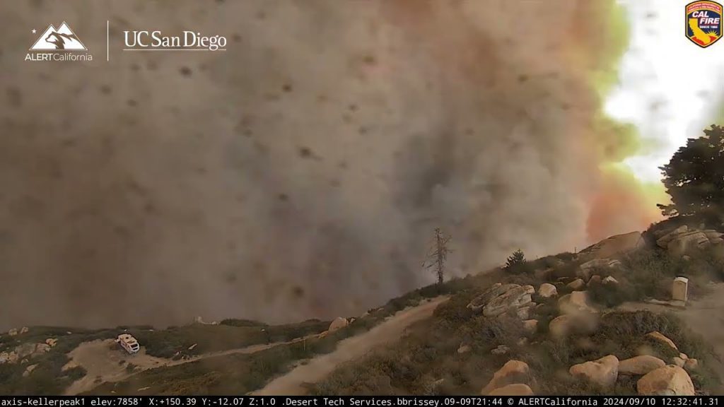 Thick wildfire smoke billows into the sky near a rugged hillside at Keller Peak as seen from an ALERTCalifornia camera.